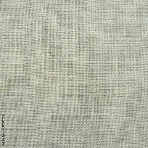 Fabric texture background. Light gray fabric with weave. Natural slightly wrinkled look of the material. Uniform copy space background. Cotton, canvas or woolen thin fabric laid evenly on the surface