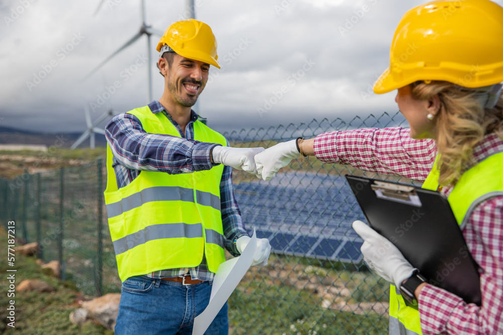Two engineers punch each other at the solar power station, teamwork concept Two engineers punch each other at the solar power station, teamwork concept