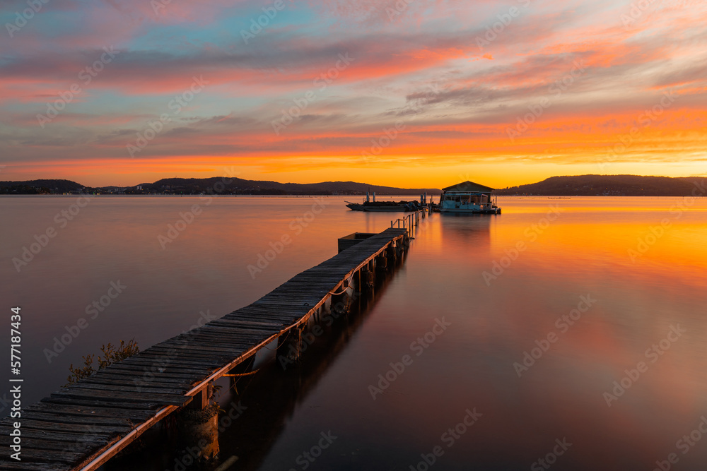 Fototapeta premium Beautiful sunrise sky over a pier at the lake.