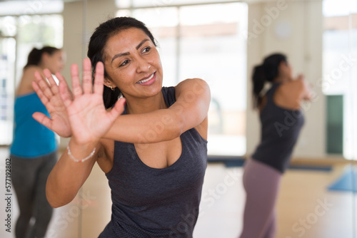 Portrait of young smiling hispanic woman dancing in modern studio