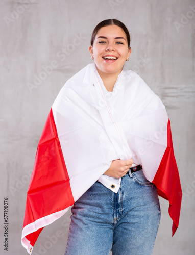 Joyful girl stands with flag of Poland in her hands. Isolated on gray background photo