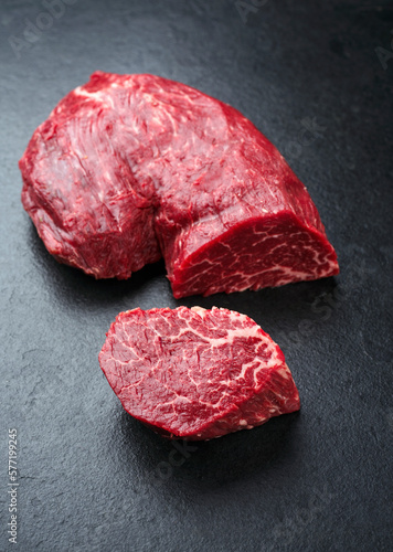 Raw Italian chianina beef fillet steak offered as close-up on a rustic black board with copy space