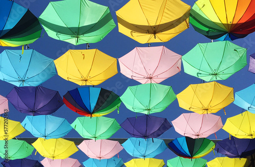 unos paraguas de colores colgados con un cielo azul photo