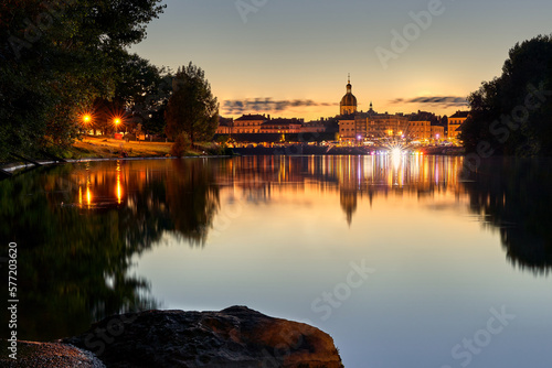 Chalon sur Saône bei Sonnenuntergang. Die Altstadt reflektiert auf der spiegelglatten Wasseroberfläche. Lichter erhellen die Uferpromenade photo
