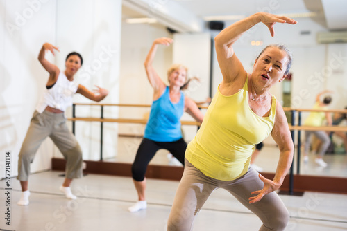 Portrait of a positive European woman enjoying energetic dancing at a group class in a modern dance studio