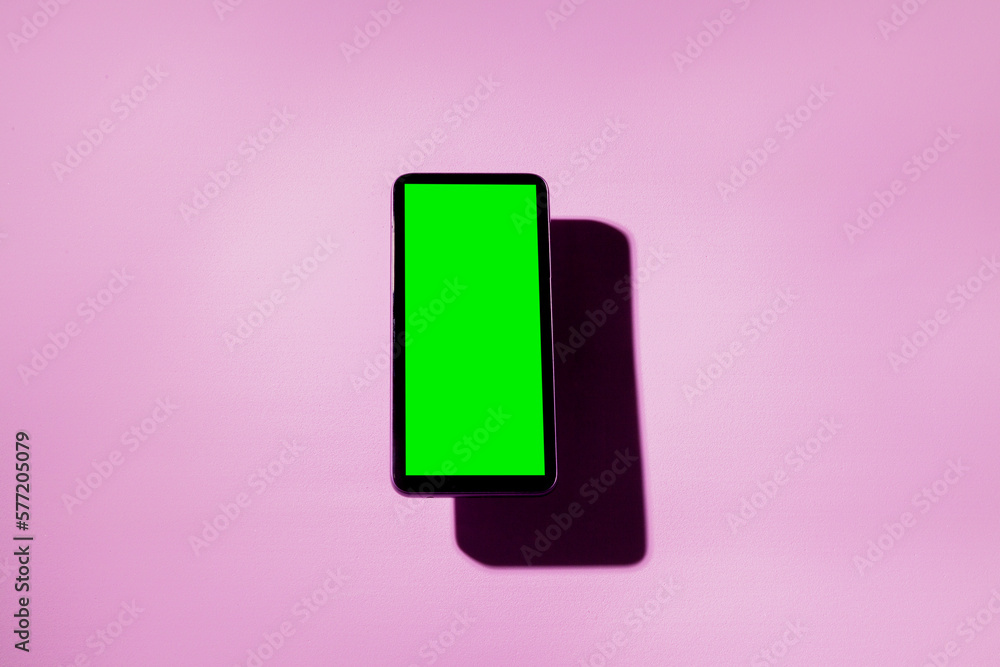Smartphone with green screen on top of a pink table. smartphone concept. Green screen concept. Smartphone with green screen on top of a pink table. smartphone concept. Green screen concept.