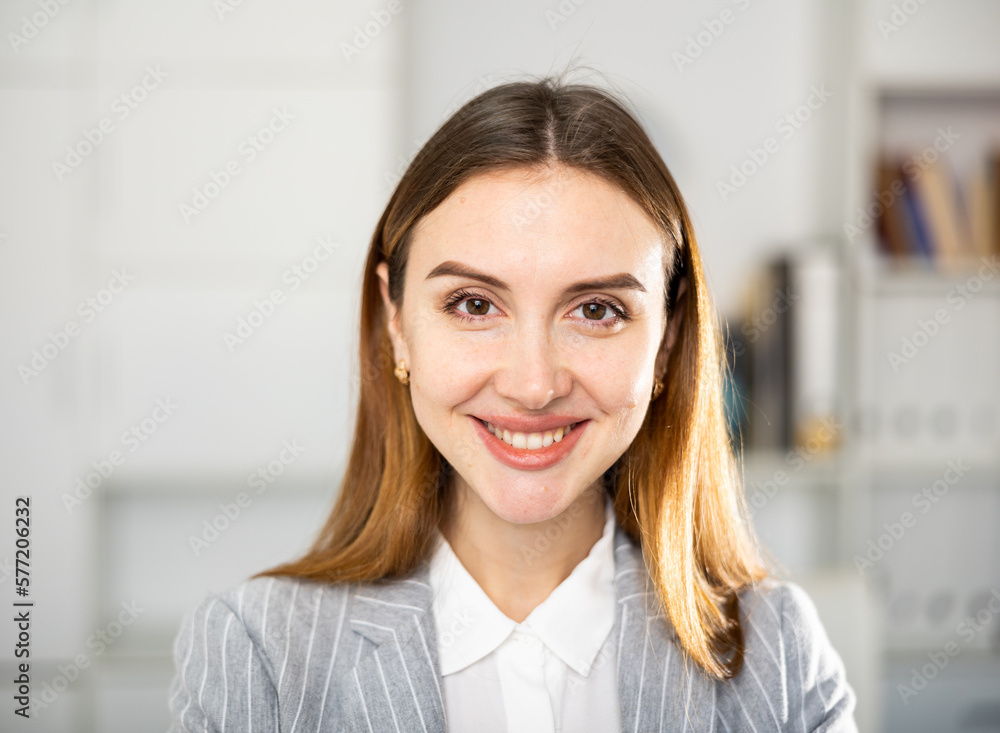 Portrait of positive young woman office worker looking at camera and smiling.