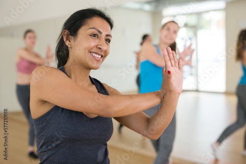 Portrait of dancing latin american woman practicing vigorous swing during group training in dance studio.