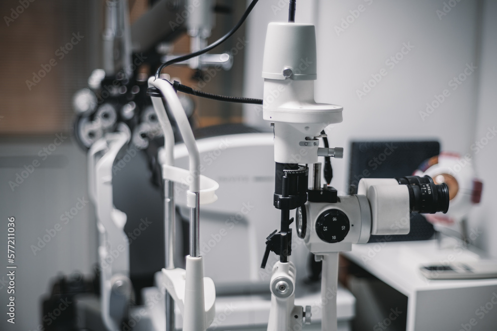 A doctor's ophthalmology office, with a white photo-coagulation laser machine in focus and surroundings, creates a sterile, clinical environment in the foreground