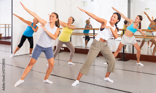 Group of women in sportswear performing contemporary dance in training room.