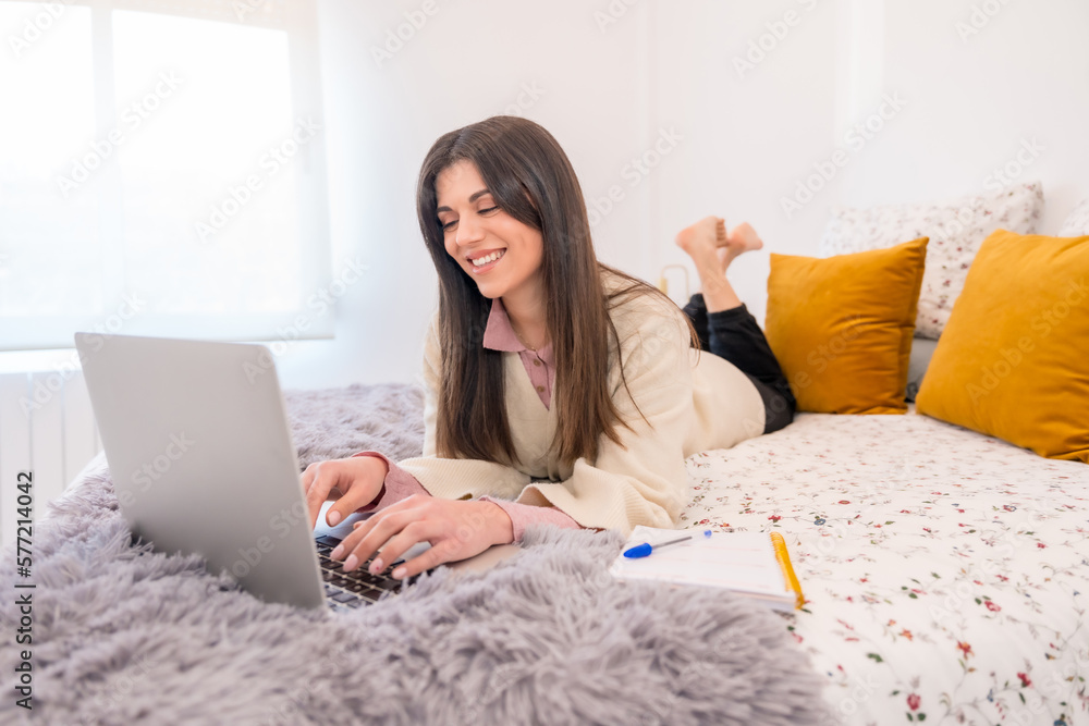 Young woman using her laptop personal computer in bed, millennial, telecommuting, teleworking Young woman using her laptop personal computer in bed, millennial, telecommuting, teleworking