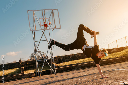 teenager boy dancing breakdance on a basketball court. hip hop culture. street and youth culture. street dancer. © Alberto