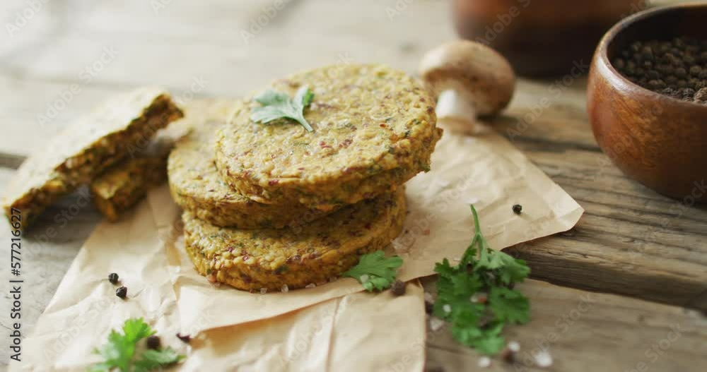Video of fresh leaves and vegetarian burgers over wooden background