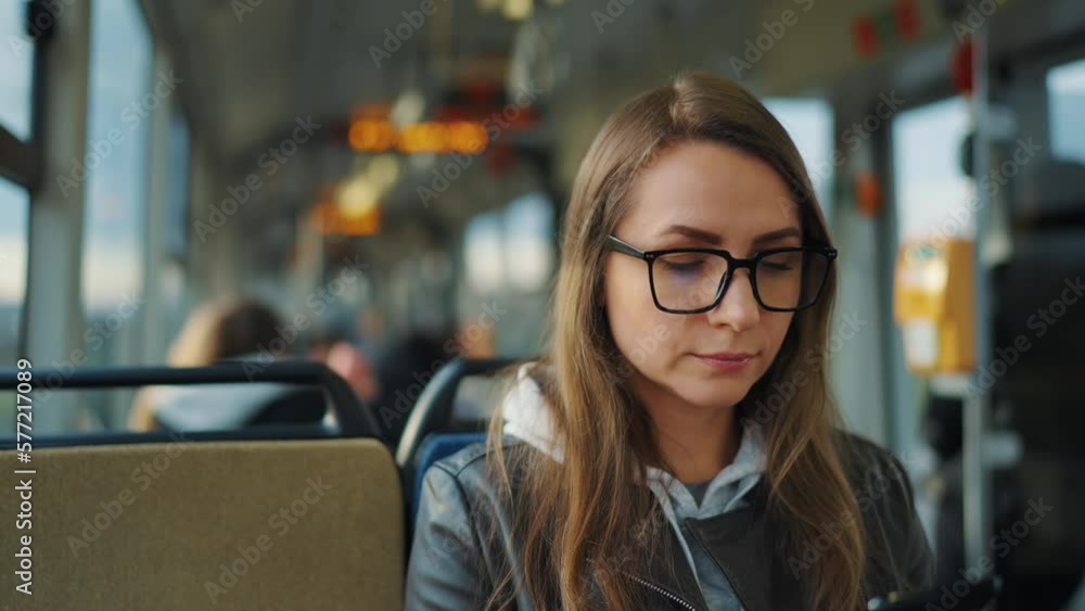 Public transport. Woman in glasses in tram using smartphone, slow motion Public transport. Woman in glasses in tram using smartphone, slow motion