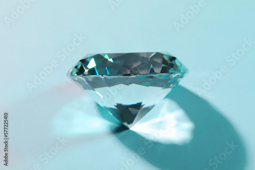 Beautiful dazzling diamond on turquoise background, closeup