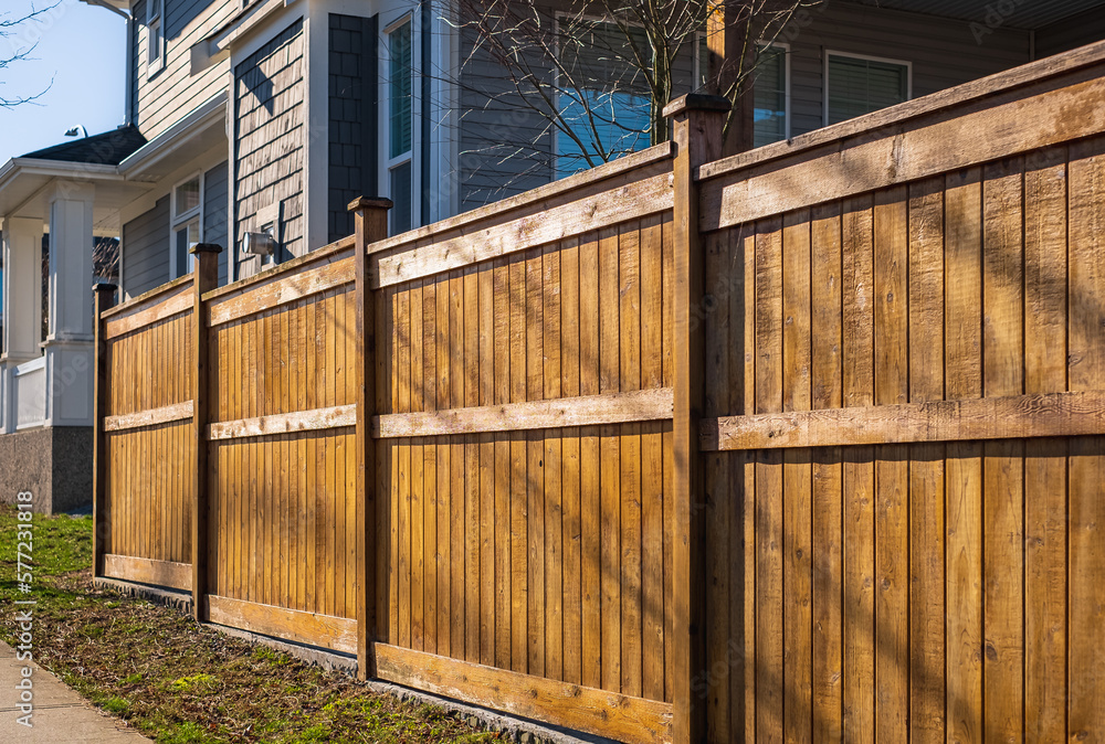 Obraz premium Nice wooden fence around house. Wooden fence with green lawn. Street photo