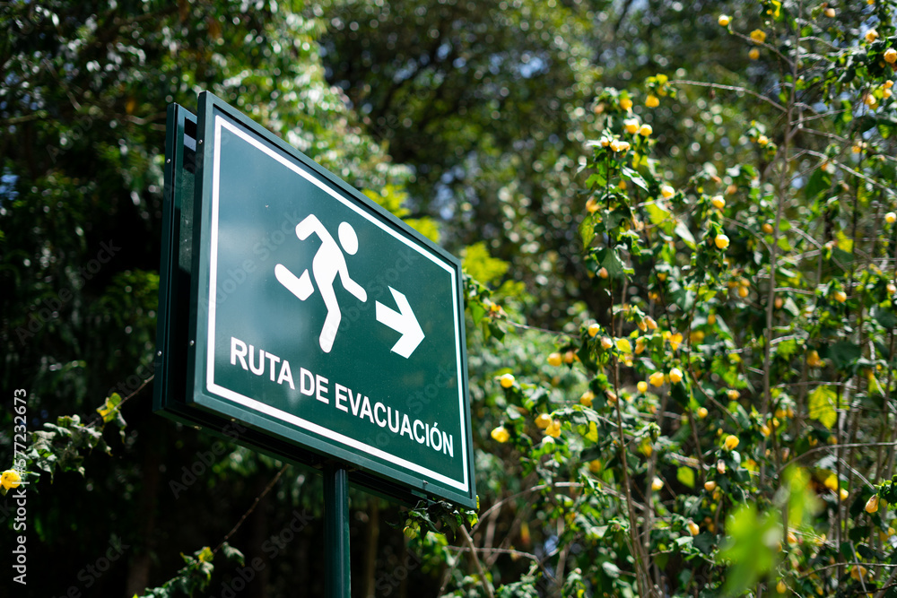 Letrero de Ruta de evacuación color verde con naturaleza de fondo