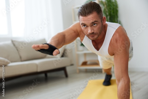 Man sports home training on the floor on a mat with dumbbells, exercises for muscle growth, pumped up man fitness trainer exercises at home, the concept of health and beauty of the body