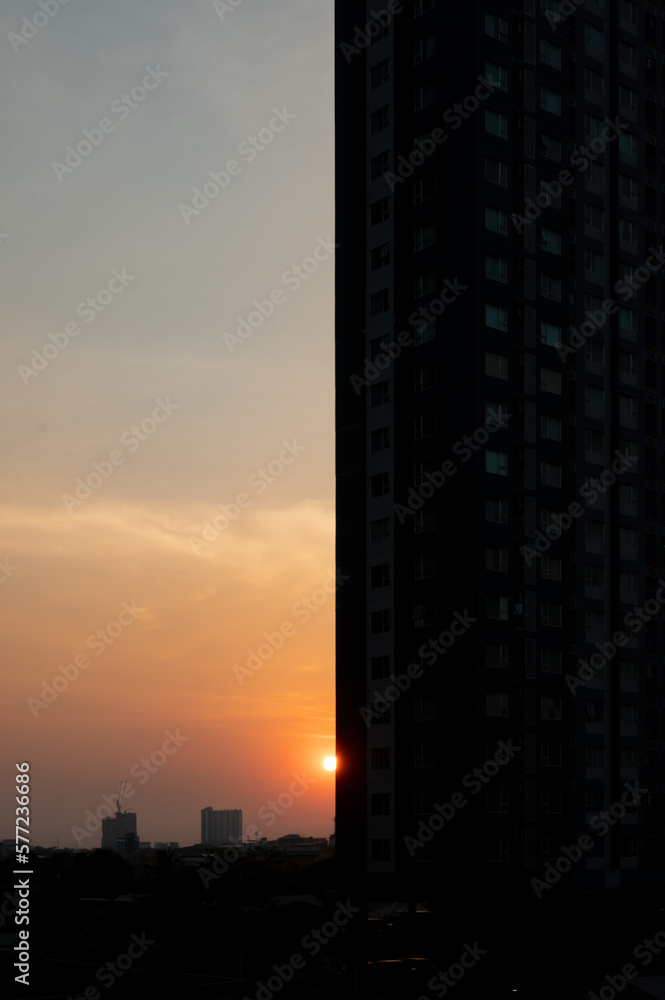 a sunset scene, half of the frame is filled with tall urban buildings.
