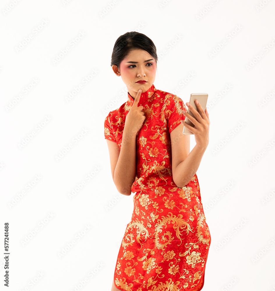 a beautiful woman in red cheongsam standing look at the phone at her left hand and touch her chin a beautiful woman in red cheongsam standing look at the phone at her left hand and touch her chin