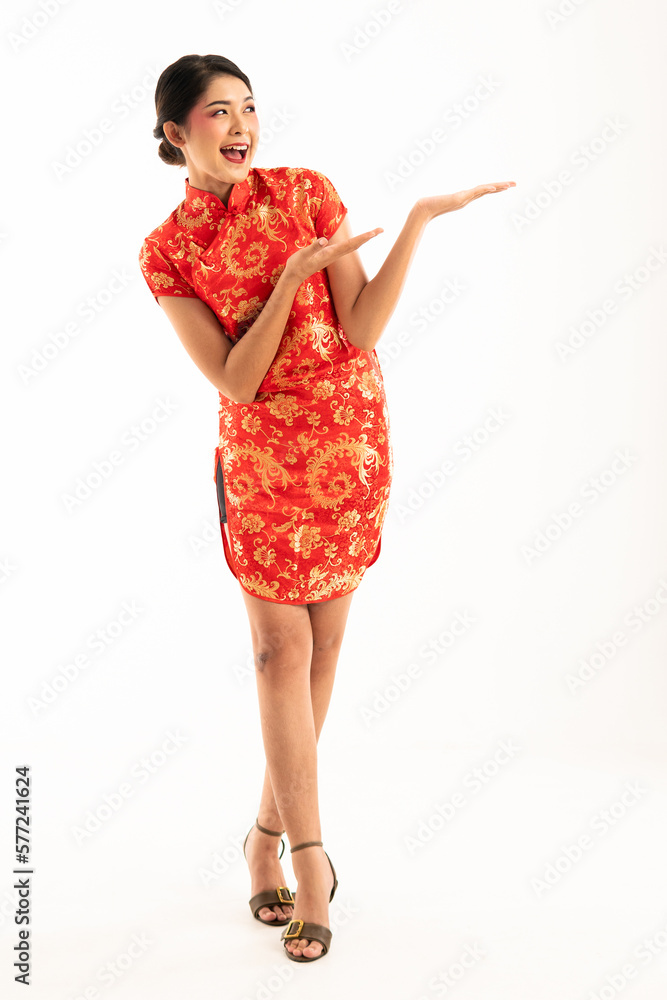 a beautiful asian woman in red cheongsam standing cross legged and pointed to her left side and smiling a beautiful asian woman in red cheongsam standing cross legged and pointed to her left side and smiling
