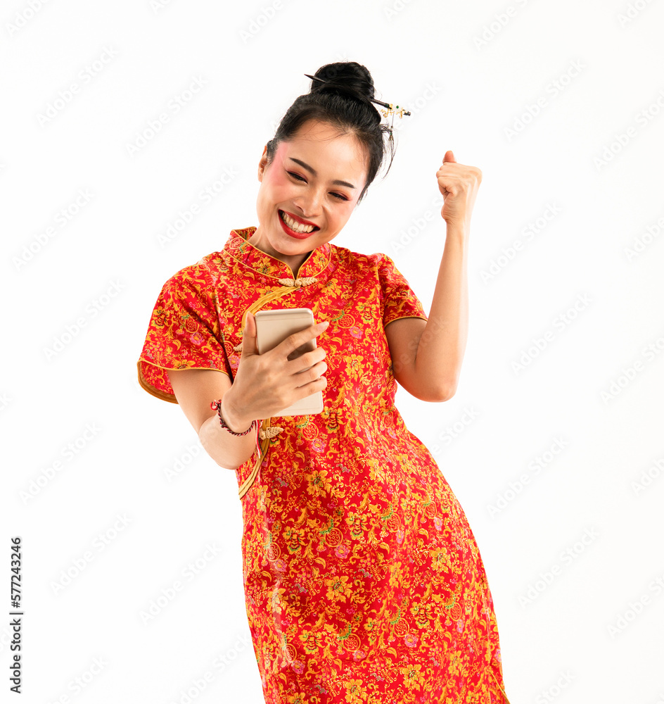 a beautiful asian woman in red cheongsam standing with clenched arm look at the phone at her hand and smiling showing her teeth a beautiful asian woman in red cheongsam standing with clenched arm look at the phone at her hand and smiling showing her teeth
