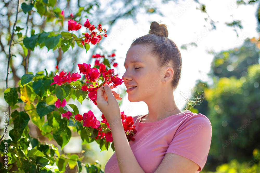 Portrait of happy beautiful girl, young positive woman is smelling beautiful yellow flowers in the garden, smiling, enjoying spring or summer day, breathing deep deeply fresh air Portrait of happy beautiful girl, young positive woman is smelling beautiful yellow flowers in the garden, smiling, enjoying spring or summer day, breathing deep deeply fresh air