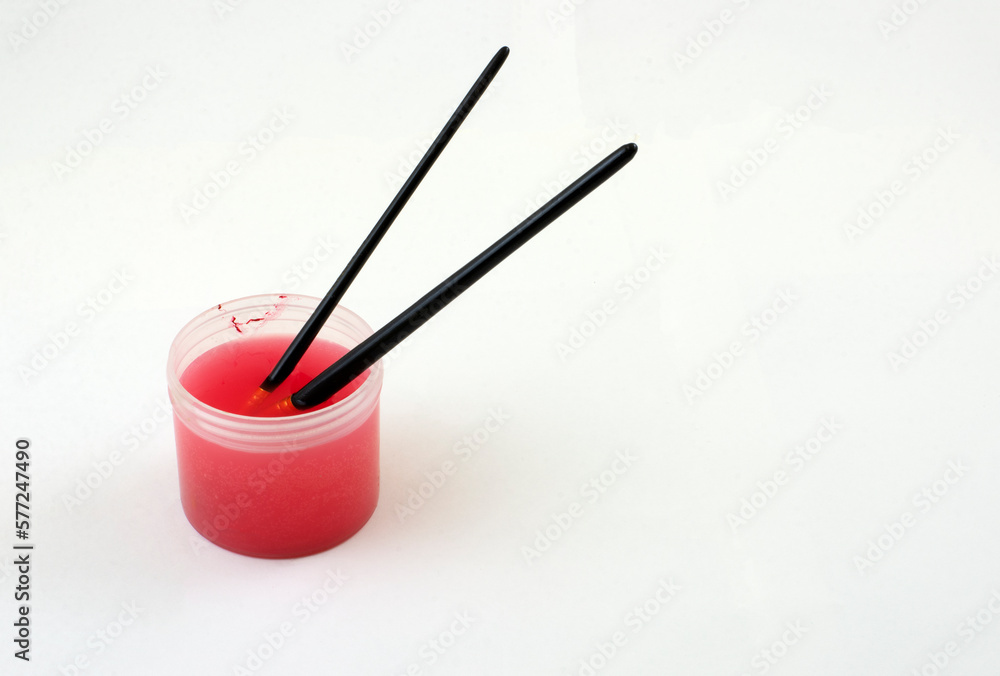 Cleaning red acrylic paint from paintbrushes by soaking in small container filled with water Cleaning red acrylic paint from paintbrushes by soaking in small container filled with water