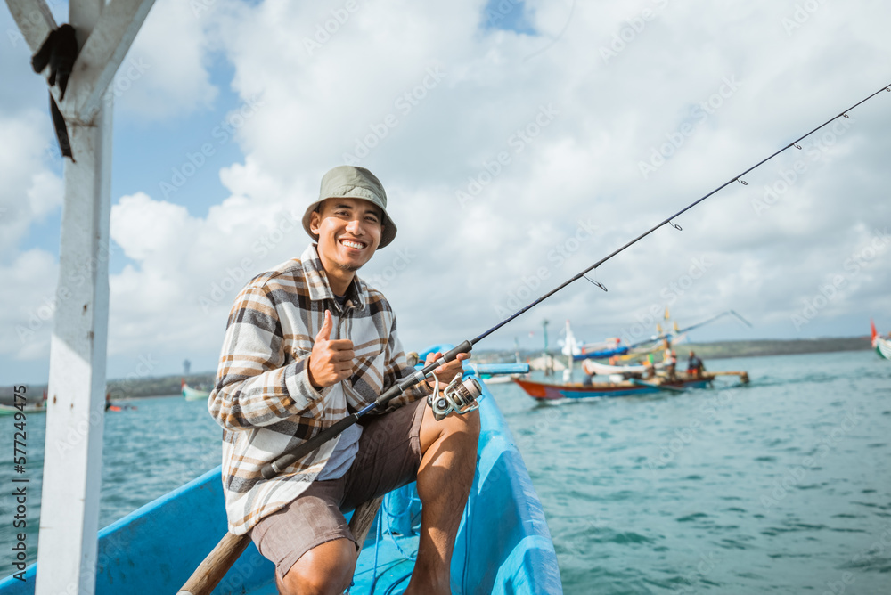 angler smiling with thumbs up while sitting on a small fishing boat at sea angler smiling with thumbs up while sitting on a small fishing boat at sea