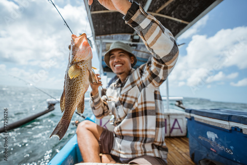 Foto big grouper caught by an Asian angler with a fishing rod