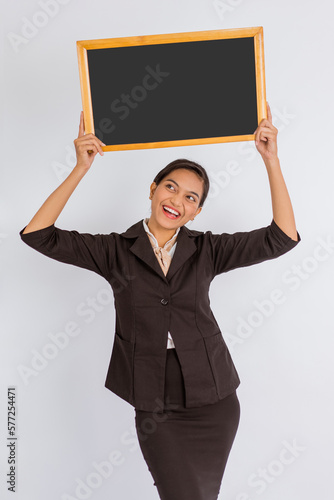 beautiful woman in formal outfit holding the blackboard up on isolated background photo