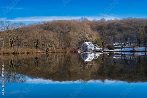 landscape with lake, white House, trees, snow and blue sky