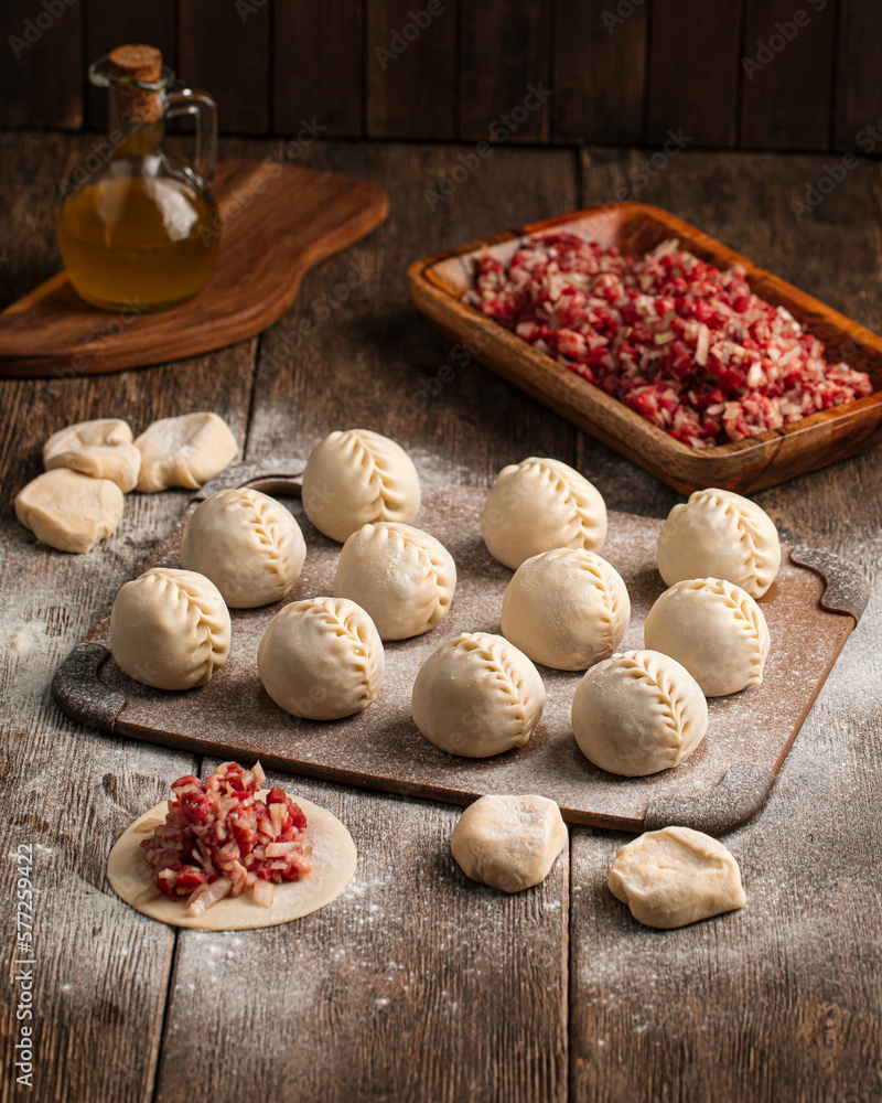 Semi-finished manti oriental dumplings on wooden board with flour Semi-finished manti oriental dumplings on wooden board with flour