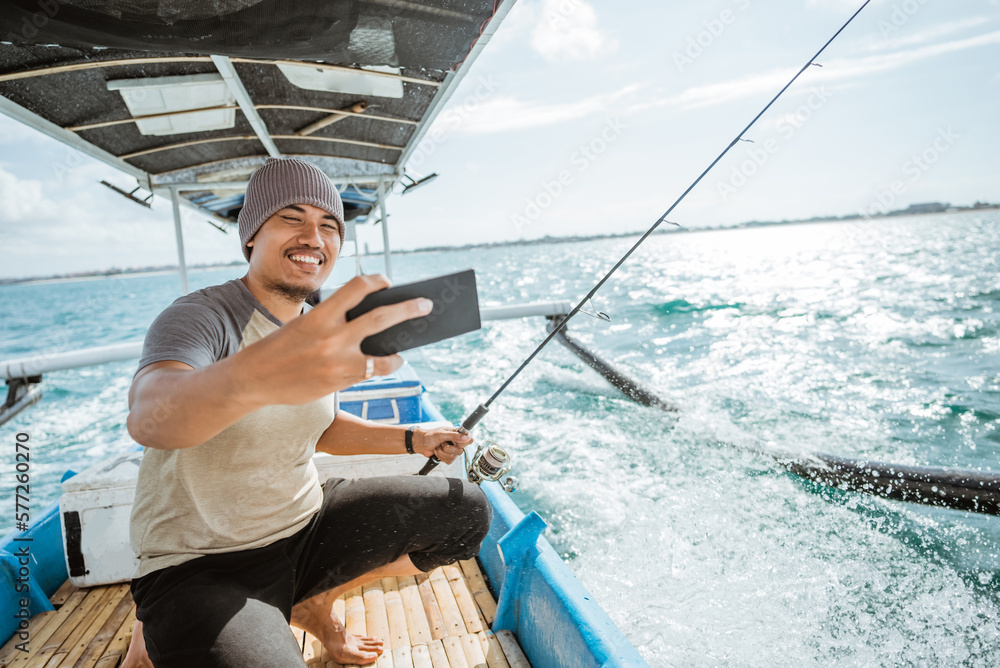 angler takes a cell phone selfie while fishing with a small fishing boat