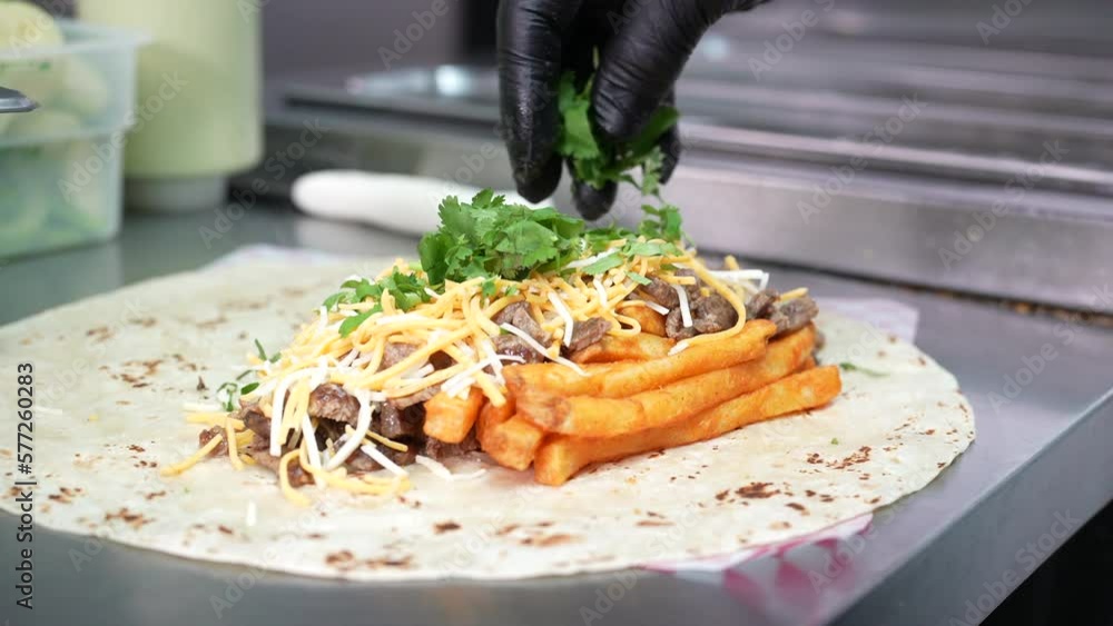 Making a California Burrito with fries, meat, cheese, cilantro - food ...