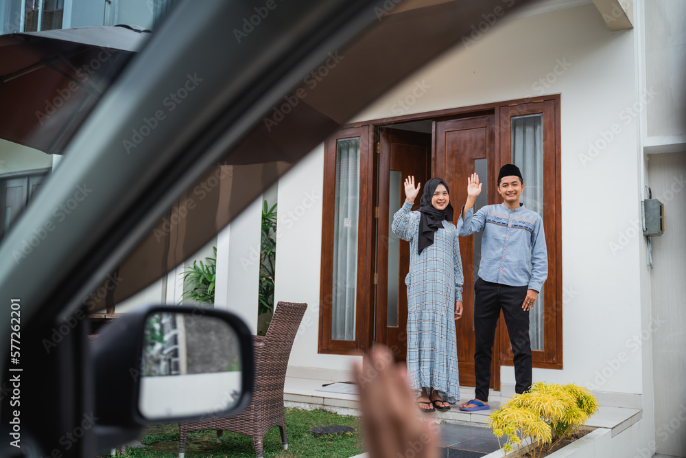 Naklejka premium view from the car window young Asian Muslim couple waving to guests in the car