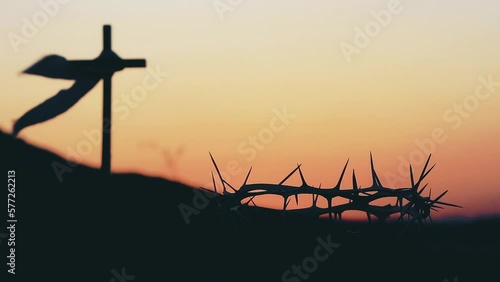 The cross and crown of thorns symbolizing the sacrifice and suffering of Jesus Christ and the red sunset, Passion Week and Lent Easter concept
