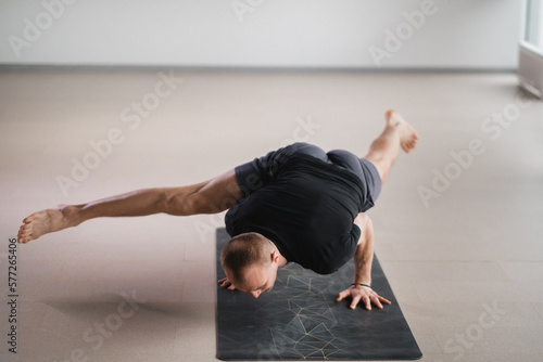 An athletically built man does yoga in the gym on a mat photo