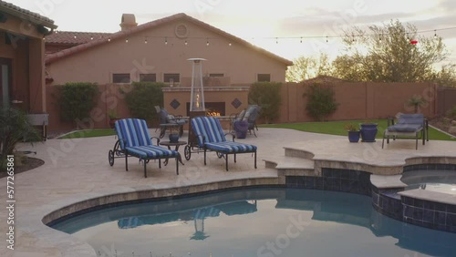 A desert landscaped backyard located in Arizona featuring
a travertine tiled pool deck outdoors kitchen and fireplace.