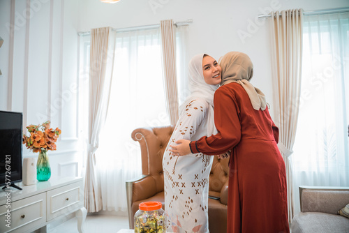 Muslim woman in veil visiting and hugging while celebrating Eid at a friend's house