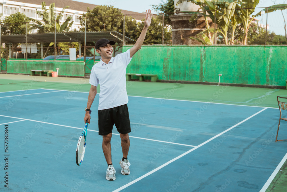 Smiling male athlete waving after the match on the tennis court