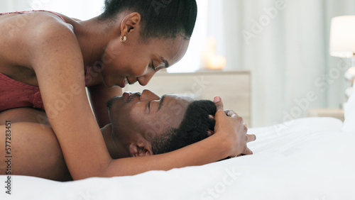 Couple in bedroom, kiss and saying I love you in bed at home. Black, young and romantic man and woman in relationship sharing intimate moment together. Happy, affectionate and loving black couple