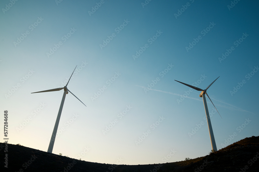 Silhouettes of wind turbines on a hill at sunrise. Silhouettes of wind turbines on a hill at sunrise.
