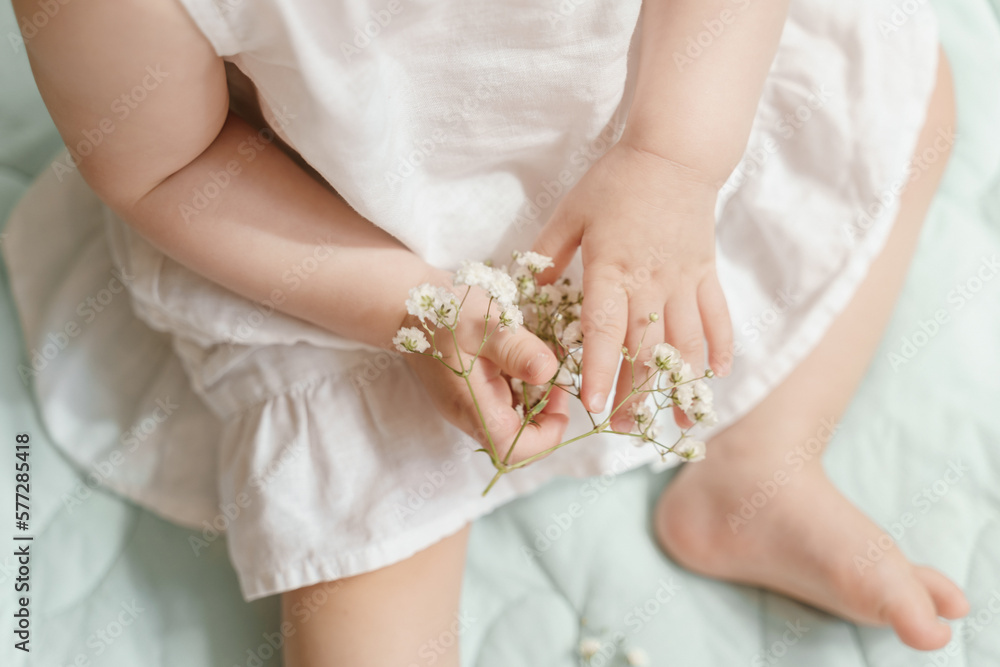 Hands of a baby girl in a white linen dress with gypsophila Hands of a baby girl in a white linen dress with gypsophila