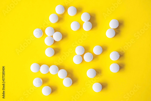 White round tablets on yellow background, top view