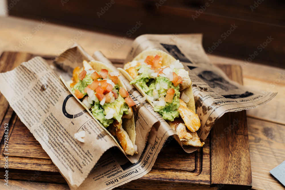 Chicken tacos with guacamole and vegetables on wooden table Chicken tacos with guacamole and vegetables on wooden table