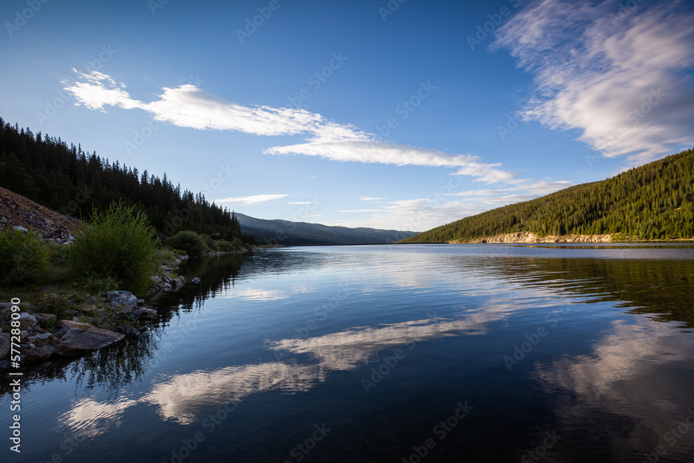 calm mountain lake with blue sky and clouds reflecting in the water