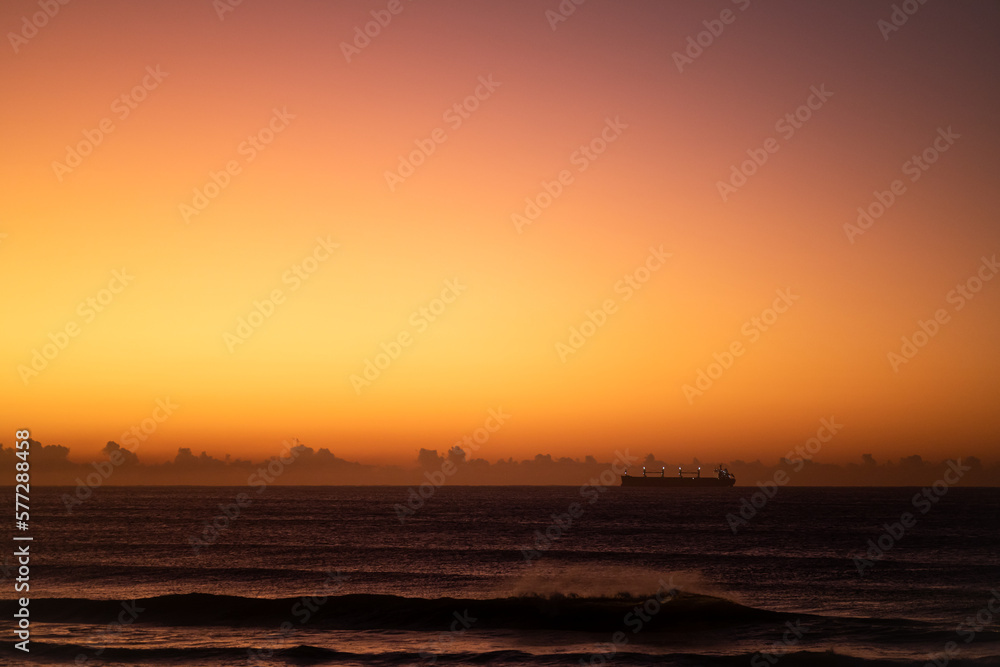 dramatic sunset over the ocean with a ship silhouette, copy space and no people