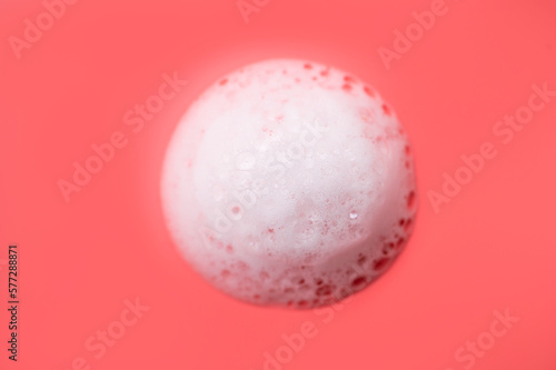 Texture of white foam with bubbles on pink background. Cosmetic foam for washing  hygiene  shampoo  soap  bathing gel  mousse. minimalistic cosmetic and medical background flat lay