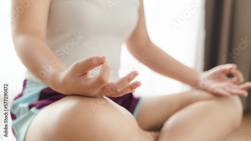 Asian woman sitting on the floor practice online yoga lessons with the computer. female having meditate training..